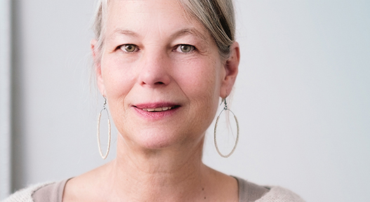 A woman with silver hair and earrings is seen close up