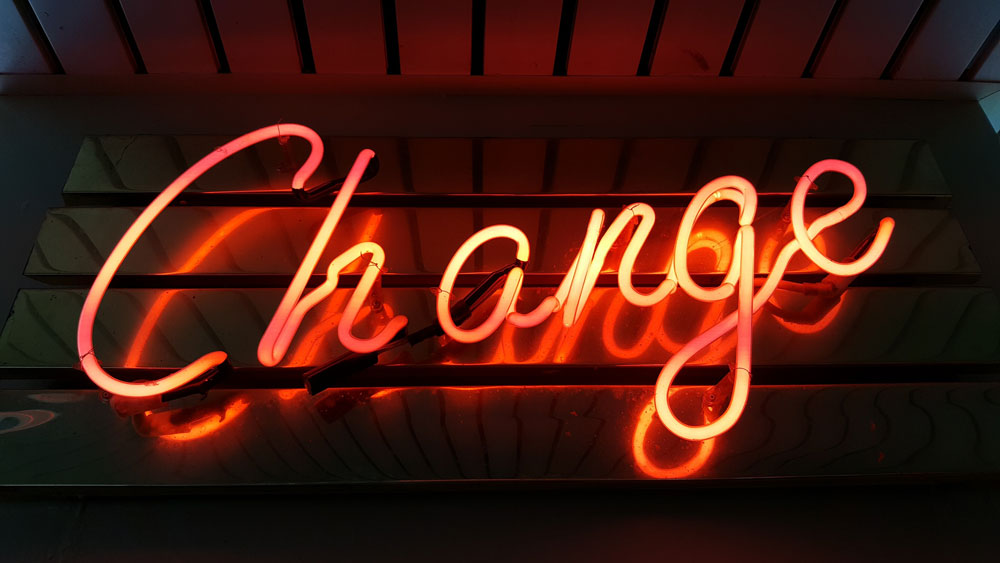 The word change in orange neon against a dark background