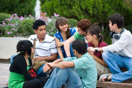 A group of seven teens relax outside of school.