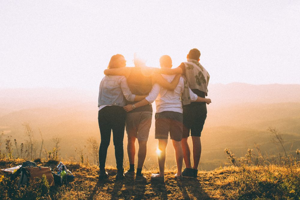 Four people look out over a valley in the setting (or rising?) sun