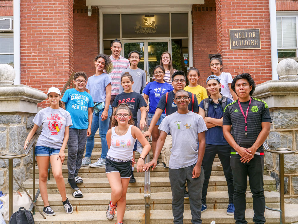 A group of middle-school students stand on the steps of Thaddeus Stevens College