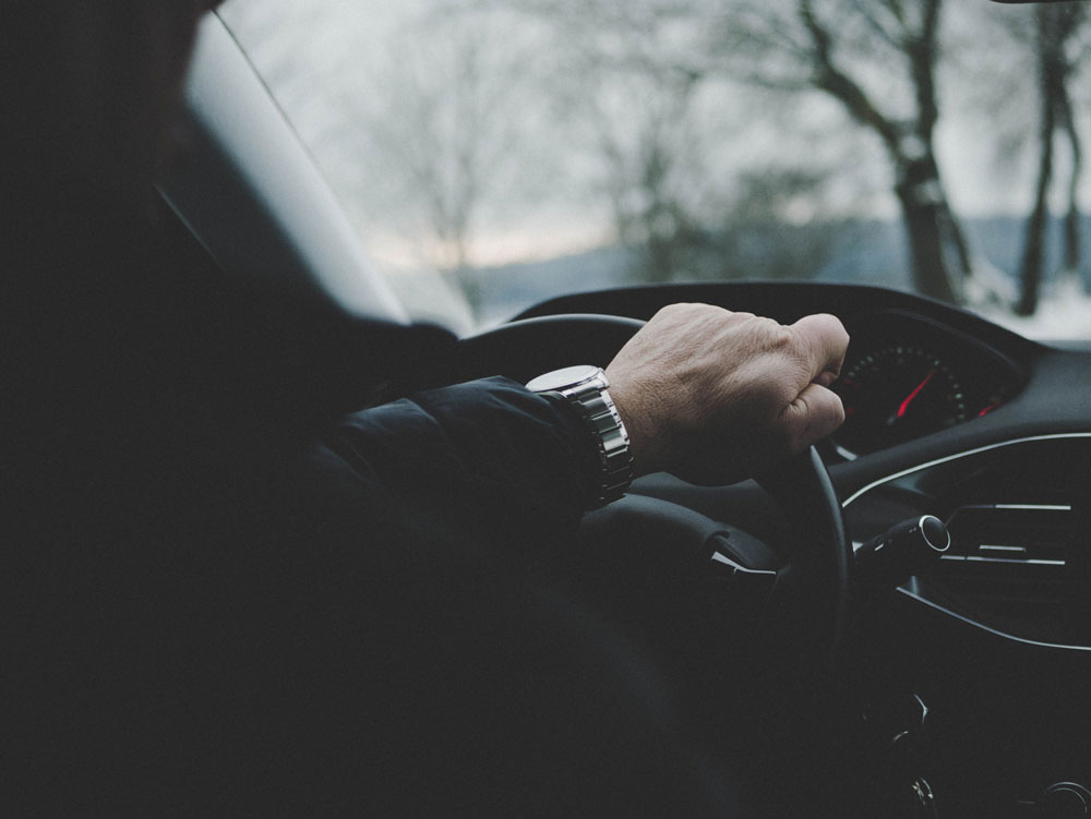 Closeup of a man's hand on a steering wheel