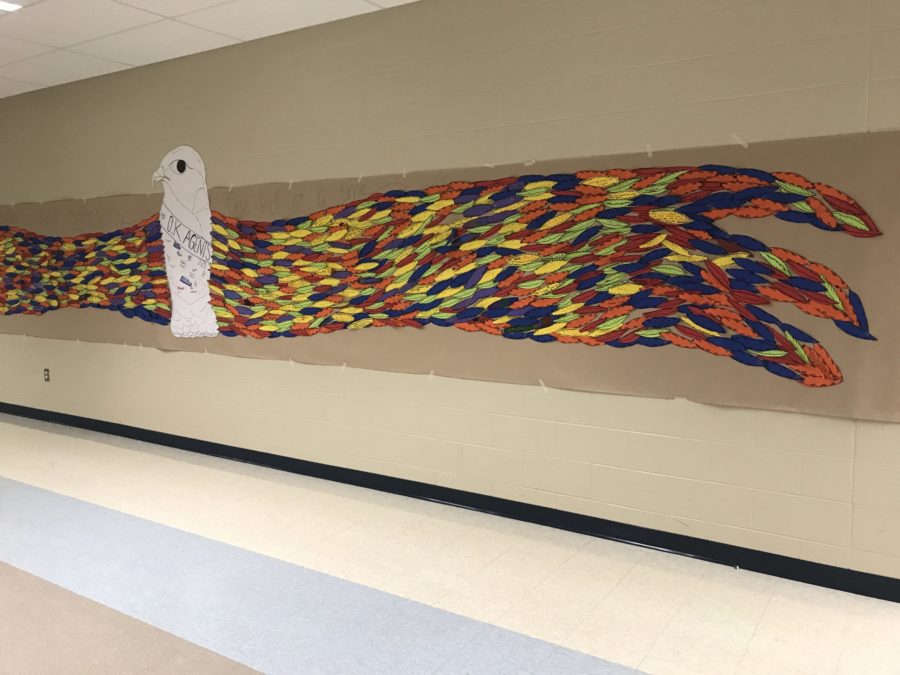 A coloful eagle stretches along the hall of a middle school. It's feathers are made up of indivual cut-outs with inspirational words written by the kids.