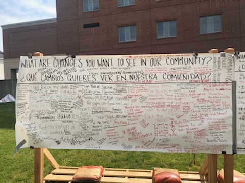 A photo of a community board in downtown Lancaster, PA asks everyone in English & Spanish, "what are changes you want to see in our community?" there are many replies, too small to read