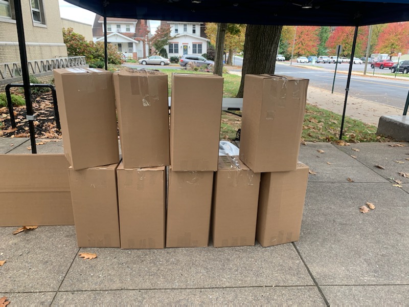 10 carboard boxes are stacked on a sidewalk