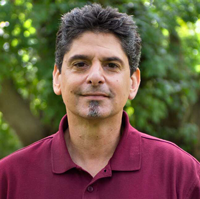 Headshot of a man in casual clothing- he is smiling slightly