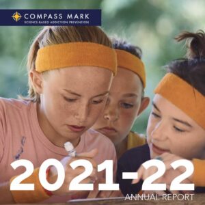 Front cover of an annual report features a closeup of 3 adolescents, the Compass Mark logo, and 2021-2022.