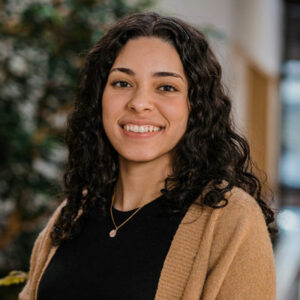 Headshot of woman in business casual clothing, in an indoor atrium, smiling