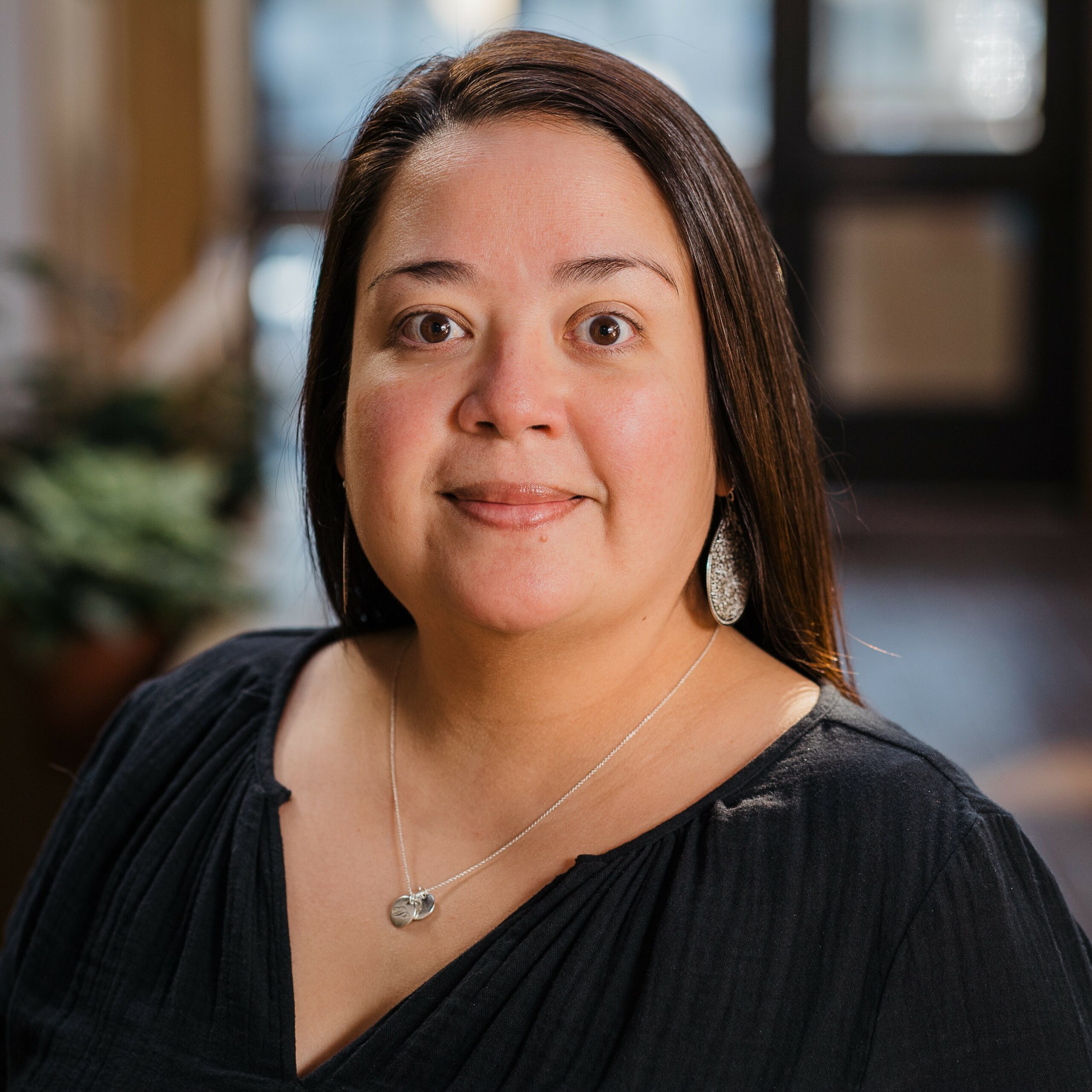 Headshot of a woman in business casual attire in a light-filled indoor atrium