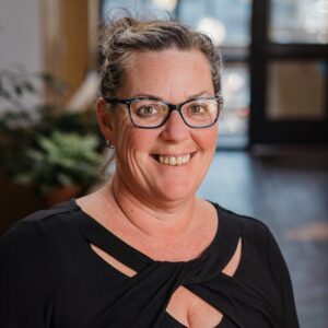 Headshot of a woman in business casual clothing in an atrium with plants