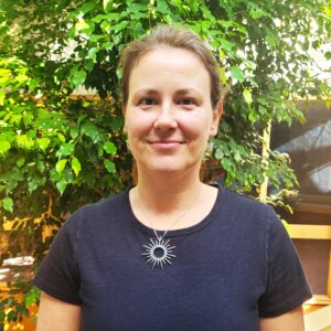 Headshot of a woman in an indoor atrium with plants