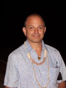 We see a many in a collared shirt with Hawaiian necklaces on. 