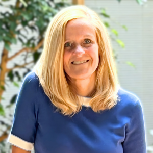 Headshot of a woman smiling in an indoor atrium with plants.